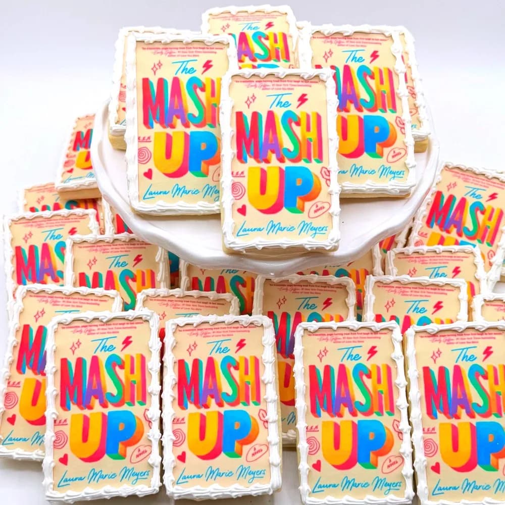 Rectangular cookies printed with a colorful Mash Up logo and a name in script, stacked on a white stand